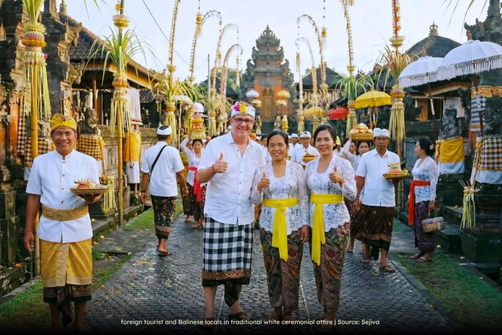 tourist and Balinese locals in traditional white ceremonial attire