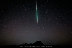 Meteor shower captured over a dark mountain landscape